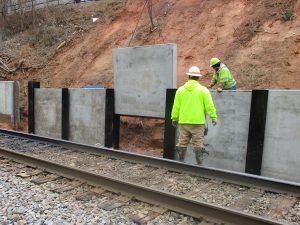 High Point Improvements - Workers place concrete panels for new retaining wall south of Wrenn Avenue